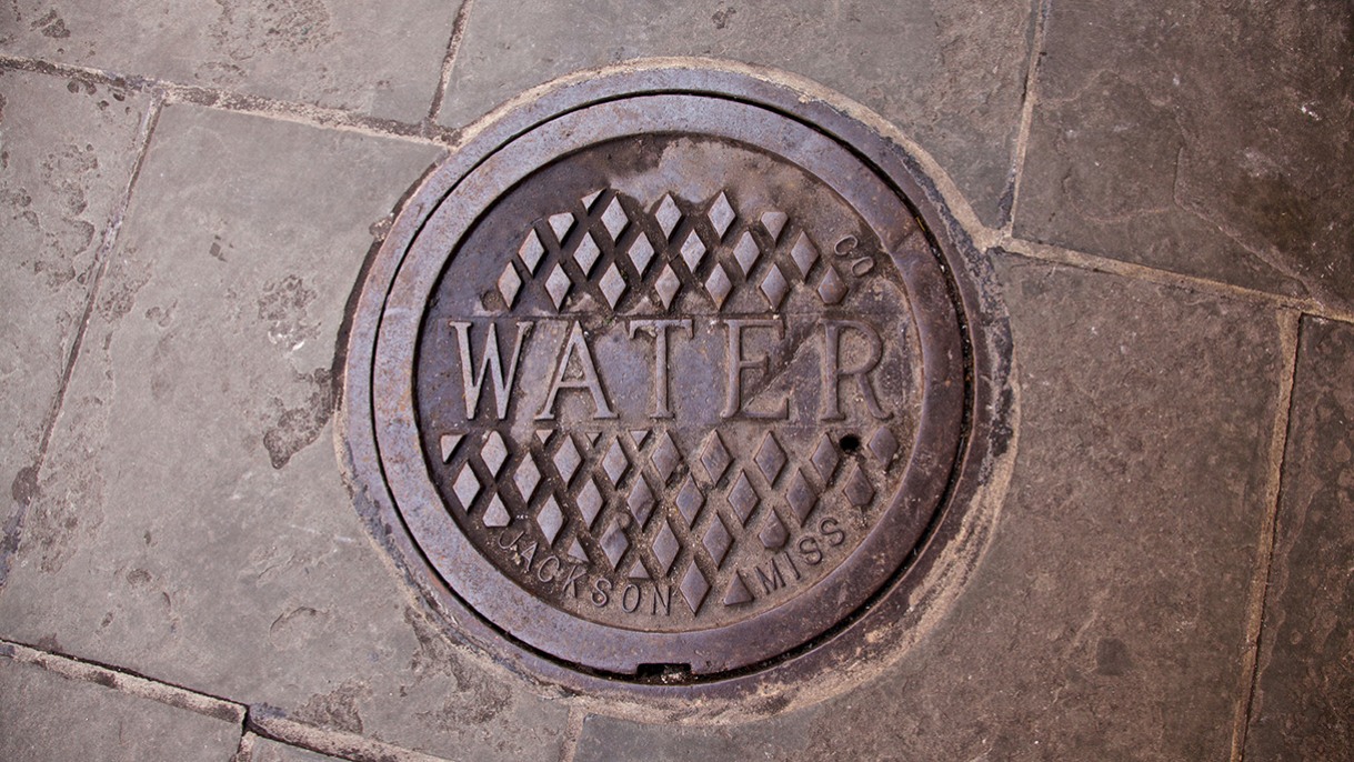Contaminated drinking water alerts cause up to 10% school absence rates in Jackson, Mississippi; Picture of manhole cover