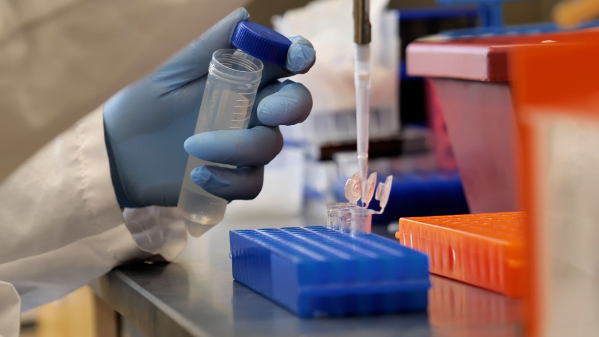 Brown, Care New England ink agreement to accelerate bringing together biomedical research; Picture: Someone working in a lab with droplets & a test tube