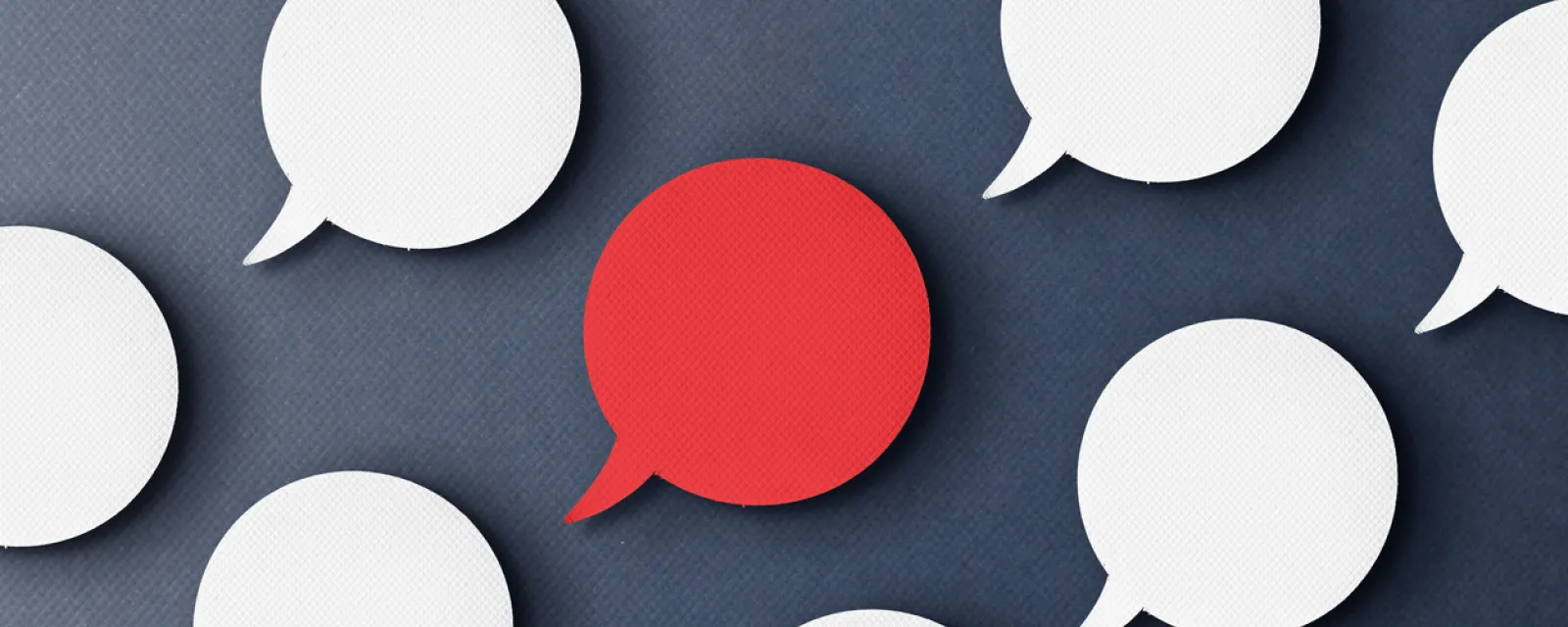 White speech bubbles with one red speech bubble depicting many voices speaking up.