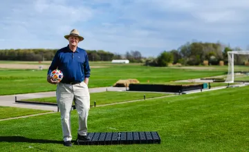 John “Trey” Rogers III standing on MSU turf grass, holding a FIFA World Cup soccer ball. 