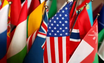 Flags of different countries, with the U.S. flag in focus and the others surrounding it. 