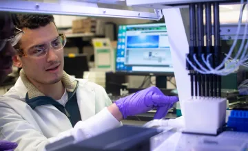 "Undergraduates David Okoh and Adam Spooner take a close look at the robotic liquid handler their research group used to make a powerful diagnostic tool simpler and more automated. All photos by Juan Siliezar/Brown University."