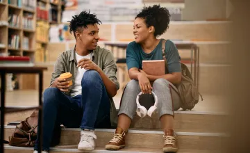 Two students of color chat in a library