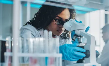 researcher looking through microscope - immigrant spotlight