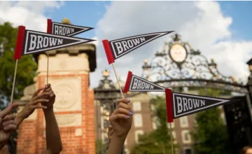 hands holding brown university flags
