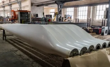 Two sets of new blades for wind turbines in a factory floor. Photo licensed from Adobe Stock.