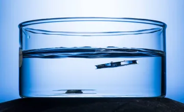 A metallic structure etched by lasers, right, floats to the top on the water's surface