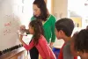 Teacher and students working on math problems using dry erase board. 