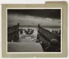Black and white photograph, on top of a folder, depicting soldiers approaching the shore of Omaha Beach on D-Day. 