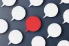 White speech bubbles with one red speech bubble depicting many voices speaking up. 
