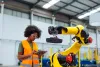 Industrial engineer programming robotic arm in factory.