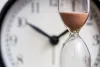 Hourglass in front of clock, depicting time passing. 