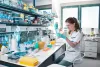 Young scientist in a lab with many shelves and containers. 