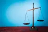 Justice scales on a wooden table with a blue background