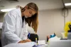 Researcher in a lab coat taking notes. 