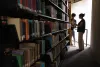 Students looking at books together at the end of a row at a college library.
