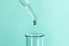 A drop falls from a pipette into a testtube; the drop contains a dollar sign.