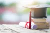 Close-up selective focus of a graduation cap or mortarboard and diploma degree certificate put on the table