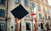 Cropped image of graduate holding academic hat and diploma with red ribbon. 
